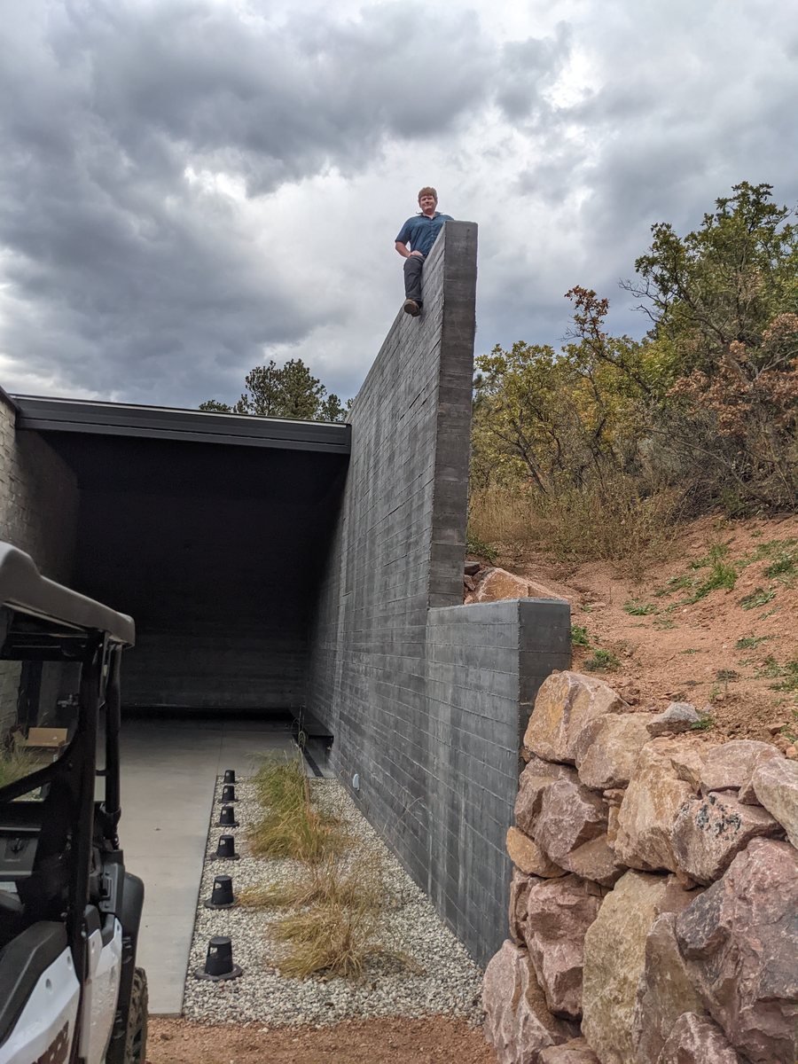 Matthew Elmore on a board-formed concrete wall at a hillside build site in Colorado